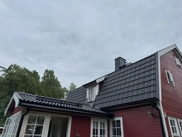Svart pannat tak med takkupa och skorsten på en röd villa