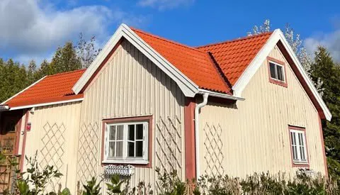 Ljus trävilla med nytt rött tegeltak mot blå himmel